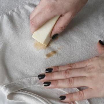 A stick of stain remover being rubbed on to a white shirt.