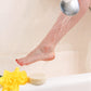A woman rinsing her leg over a bathtub with a circular lotion bar siting next to a yellow flower on the edge of the tub.