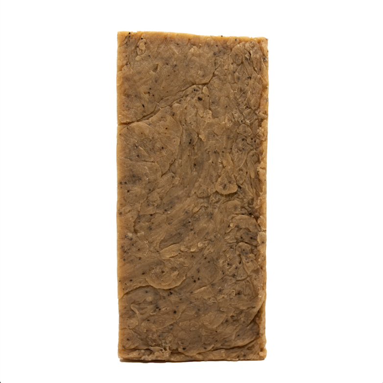 Brown soap bar with black coffee specks on a white background