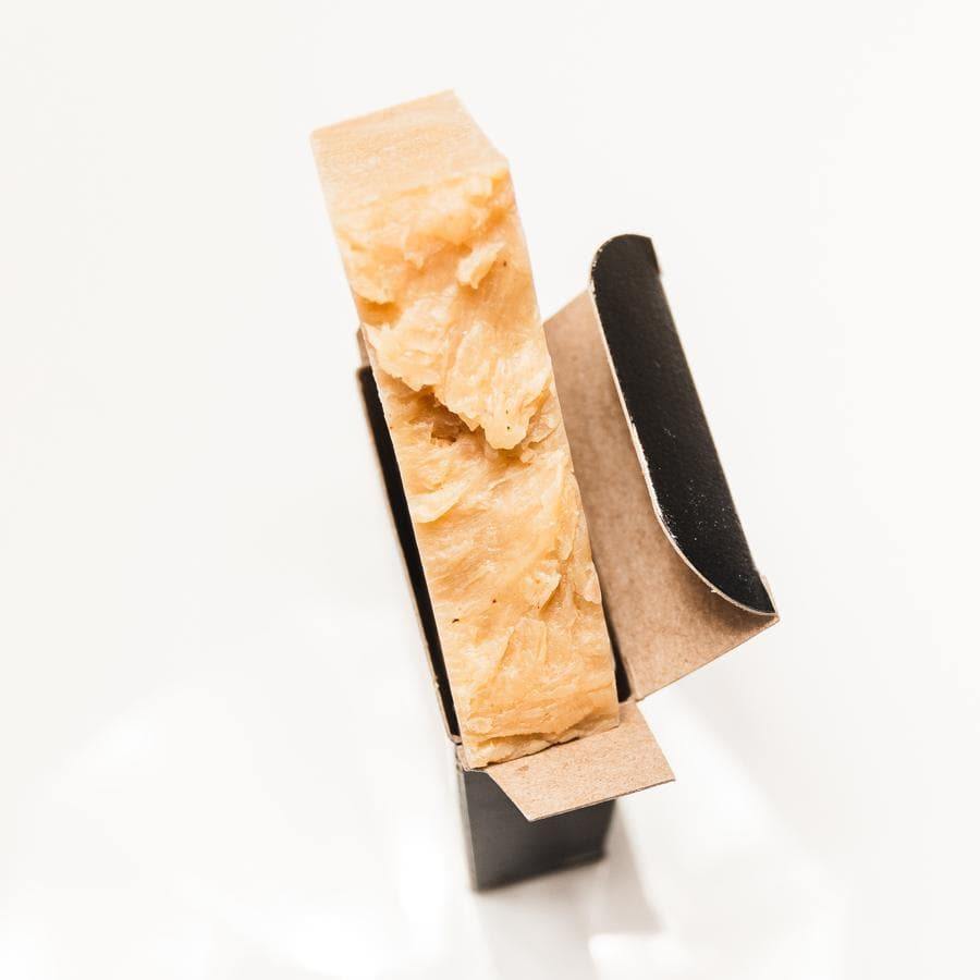 Pale orange soap bar in black PCW cardboard packaging with a white background.